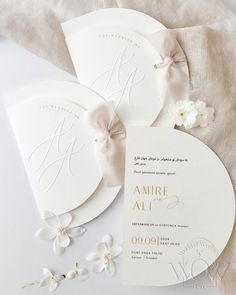 the wedding stationery is laid out on top of each other, with white flowers