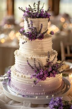 a white wedding cake with purple flowers on top