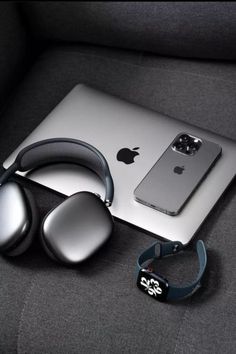 an apple laptop and headphones are sitting on a couch next to a pair of earbuds