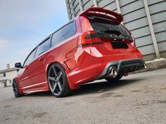 the rear end of a red car parked in front of a building