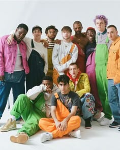 a group of young men standing and sitting next to each other in front of a white background