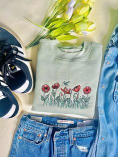 a pair of blue jeans and a t - shirt with flowers on it next to shoes