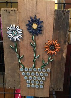 an art piece made out of soda cans and flowers on a wooden board with wire