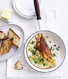 two plates with food on them next to bread and butter