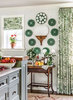 a kitchen with green plates on the wall and curtains in the window, along with an island