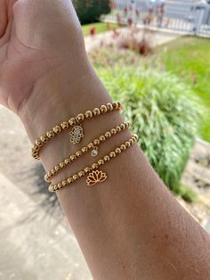 14K gold filled beaded stretch bracelets with 18K gold filled charms- classic and minimalist. Perfect for stacking and layering. Comfortable and light weight to wear. They are rust and tarnish resistant. Made with 14K gold filled beads in 3, 4 and 5mm. You can wear these as a single or add and create your stack. Each can be worn casually or dressed up. Choose your bead size 3, 4 and 5 mm and either choose to leave it plain or from one of three beautiful and elegant charms. Charm choices include: 4mm 18K gold micro pave cubic zirconia (cz) circle pendant, 18K gold filled lotus pendant and 18K gold filled CZ micro pave Hamsa evil eye charm. All bracelets are lead free, nickel free and hypoallergenic.  All bracelets are made to order and available in four sizes:  6 inches 6.5 inches 7 inches Gold Hand-strung Stretch Bracelet In 14k Gold-filled, Spiritual Gold Beaded Bracelets With Charms, Gold Stretch Bracelet With Charms As Gift, Gold Stretch Bracelet With Charms For Gift, Flexible Gold Bracelet With Tiny Beads, Dainty Gold Stretch Bracelet With Gold Beads, Gold Spiritual Charm Bracelet For Everyday, Dainty Gold Bead Stretch Bracelet, Dainty 14k Gold-filled Stretch Bracelet With Gold Beads