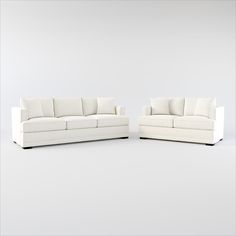 two white couches sitting next to each other on top of a gray flooring