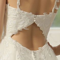 the back of a woman's wedding dress with white lace and buttons on it