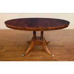 an oval wooden table with four legs on a hard wood floor