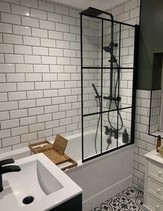 a bathroom with a sink, tub and shower head is shown in black and white tiles