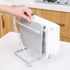 a person is holding three towels on a towel rack in the middle of a kitchen