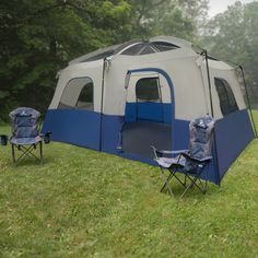 a tent set up in the grass with two chairs