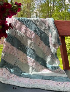 a blanket sitting on top of a wooden bench next to a vase with red flowers