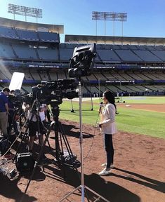 a camera set up in front of a baseball field with people on the sidelines