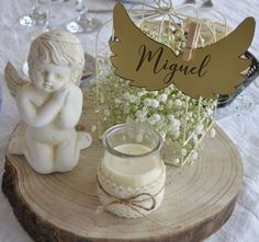 a candle and angel figurine sitting on a wood slice with baby's breath