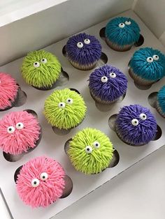 a box filled with cupcakes covered in frosting and decorated like monster eyes