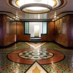 an empty hallway with decorative flooring and wooden doors