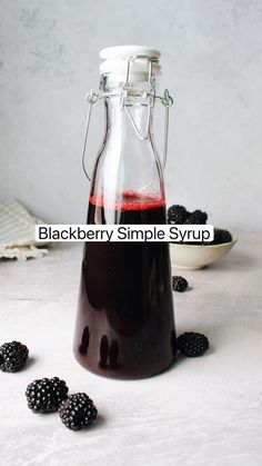 blackberry simple syrup in a glass bottle with blackberries around it