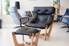 two black leather chairs and one blue chair in a living room with white tile flooring