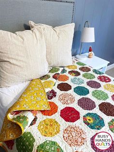 a bed with a quilt on top of it and two pillows next to the headboard