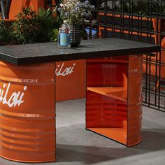 an orange table with two soda cans on it and flowers in a vase next to it