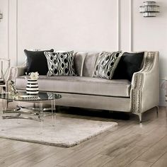 a living room with white walls and wooden flooring, black and white pillows on the couch