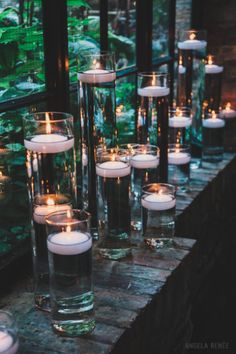 candles are lined up in glass vases on a table