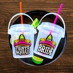 two plastic cups with straws and neon colored lids are sitting on a black plate