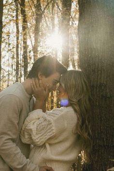 a man and woman kissing in the woods