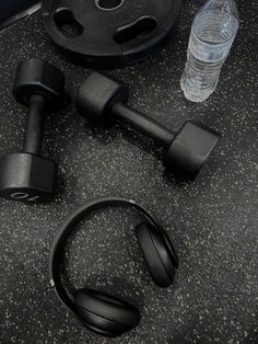 there are headphones, water bottle and dumbbells on the floor next to each other