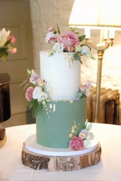 a white and blue wedding cake with flowers on the top is sitting on a table