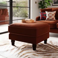 a living room with a chair, ottoman and rug in front of a sliding glass door