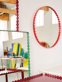 a mirror that is on the wall in front of a table with chairs around it