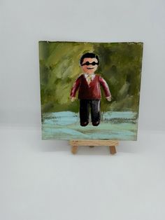 a painting of a man in red shirt and black pants standing on a wooden easel