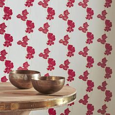 two bowls sit on a table in front of a wall with red flowers and gold trim