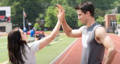 a man and woman giving each other high fives on a track with the words now playing get tickets now