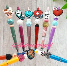 several pens with different designs on them sitting in front of a wooden table next to flowers