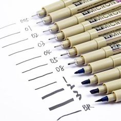 several pens are lined up next to each other on top of a sheet of paper