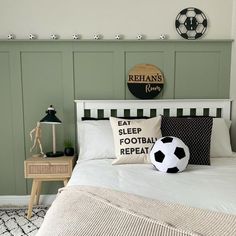 a bedroom with green walls and white bedding has a soccer ball on the pillow