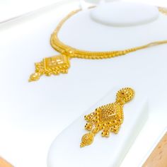 This 22k gold necklace set features a graceful design with elegant hanging tassels, perfect for adding sophistication to any look. Weighing 30.0 grams, the set is crafted from radiant yellow gold, with a 16-inch necklace that includes 1.75-inch adjustable links and a secure hook lock. The matching 1.75-inch earrings, fitted with screw-back posts, complete the ensemble with a refined touch. The tassel design adds movement and charm, making this set ideal for those who appreciate timeless elegance with a modern flair, perfect for special occasions PRODUCT DETAILS Gold Purity(karat): 22k Gold Weight(grams): 30.0 Item Finish: Yellow Gold Set Length: 16" Drop Length: 1.5" Adjustable Links: 1.75" Links Lock Style: Hook Lock Matching Earrings: Included Earring Length: 1.75" Earring Post: Screw Ba 22k Gold Necklace Set, Hanging Tassels, 22k Gold Necklace, Bridal Jewelry Necklace, Precious Stones Rings, Diamond Pendant Sets, 16 Inch Necklace, Fancy Necklace, Fancy Rings