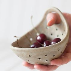 a person holding a bowl with cherries in it