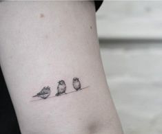 three small birds sitting on the side of a woman's leg, one is black and white