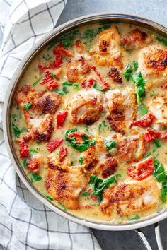 a skillet filled with chicken and spinach covered in sauce on top of a table