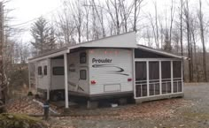 a small white trailer sitting in the middle of a forest