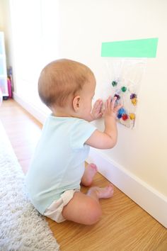 a baby sitting on the floor playing with magnets and paper clips in front of a wall