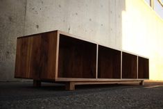 a wooden shelf sitting in front of a building on the side of a road next to a cement wall