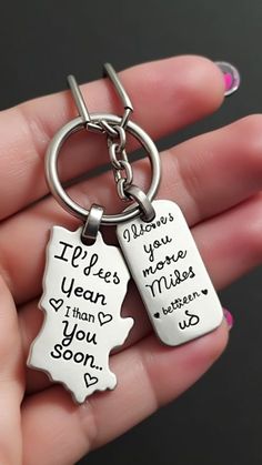 a person holding two key chains with words on them