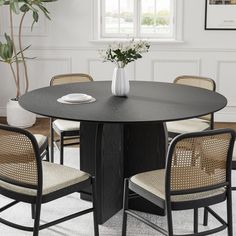 a round dining table with four chairs around it and a vase on the table top