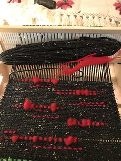 a close up of a weaving machine with red yarn on the top and bottom of it