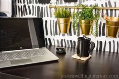 an open laptop computer sitting on top of a wooden desk next to two planters